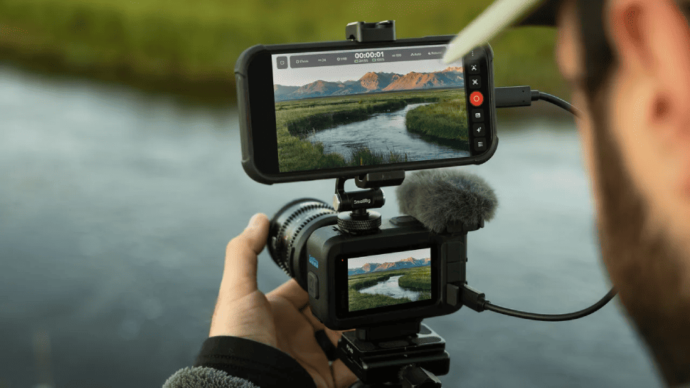 iPhone, закреплённый над камерой GoPro MISSION 1 PRO, используется как расширенный монитор во время съёмки у реки